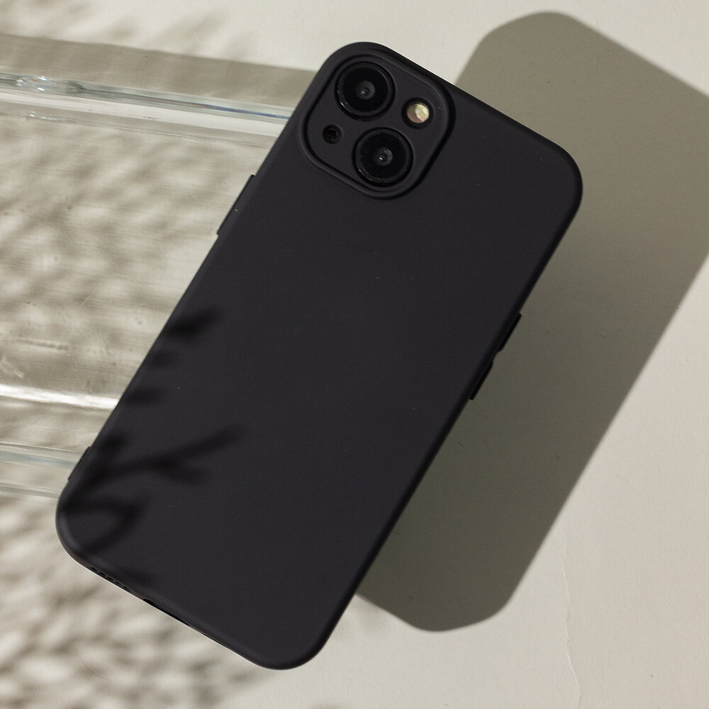 Czarna nakładka ochronna na smartfon z widocznymi wycięciami na aparat i lampę błyskową. Nakładka leży na jasnej powierzchni z delikatnym cieniem w tle.