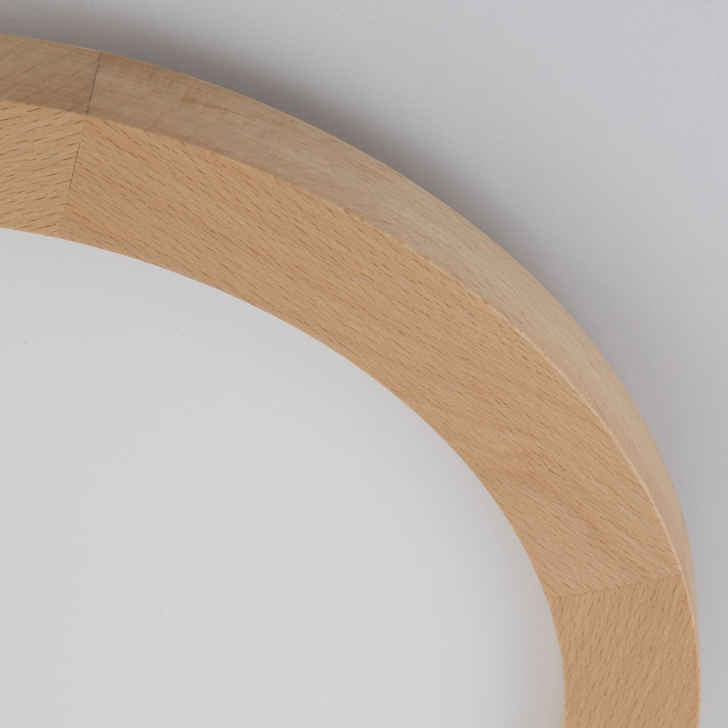 Fragment okrągłego plafonu z drewnianą ramą w kolorze jasnego buku i białą powierzchnią wewnętrzną.