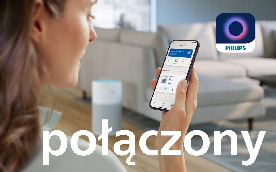 Osoba trzyma smartfon z aplikacją do sterowania urządzeniem, w tle widoczny oczyszczacz powietrza. Na obrazie znajduje się logo PHILIPS oraz duży napis \'połączony\'.