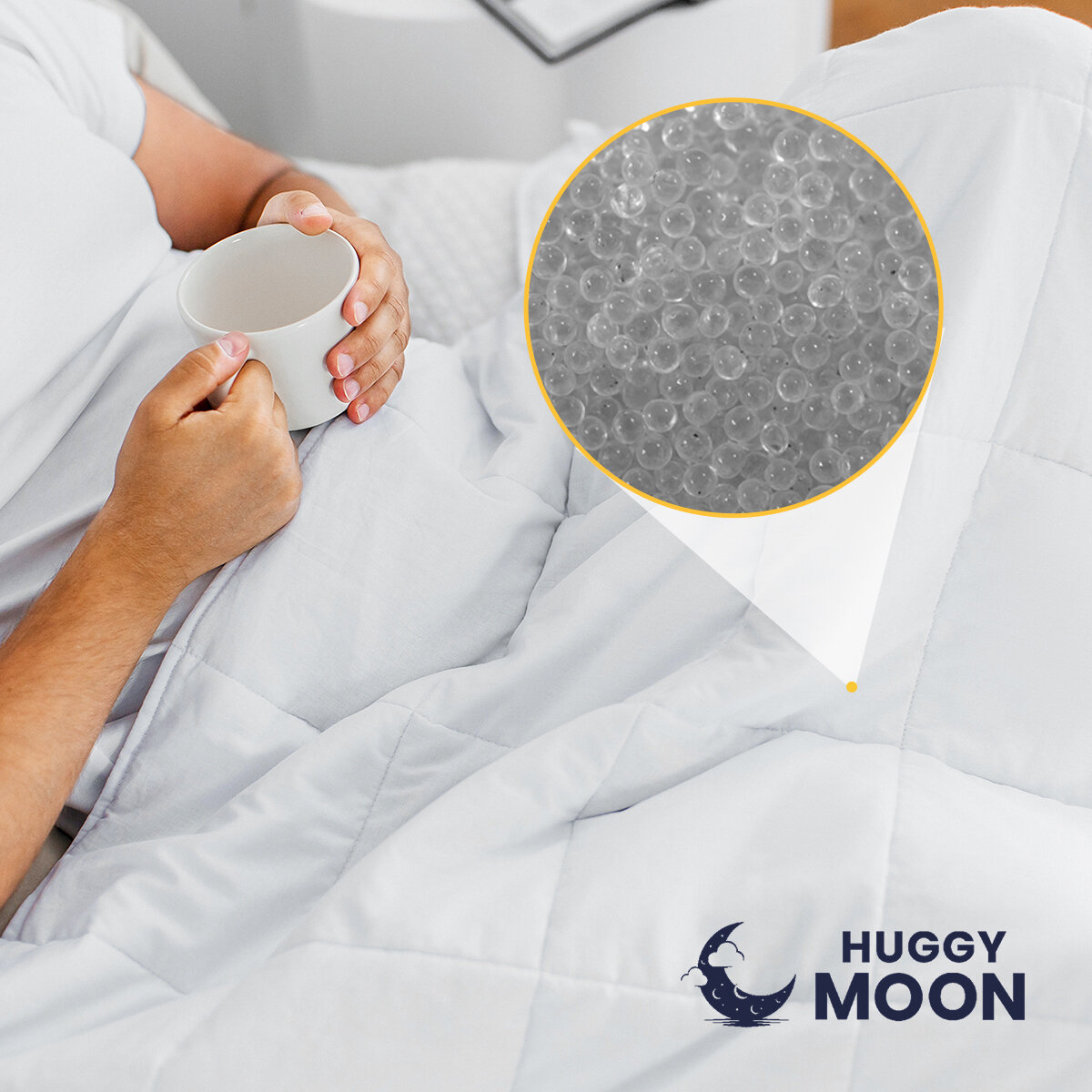 Osoba trzymająca biały kubek siedzi pod białą kołdrą. W prawym dolnym rogu widoczne jest logo \'HUGGY MOON\', a obok powiększenie struktury materiału kołdry z widocznymi małymi kulkami.