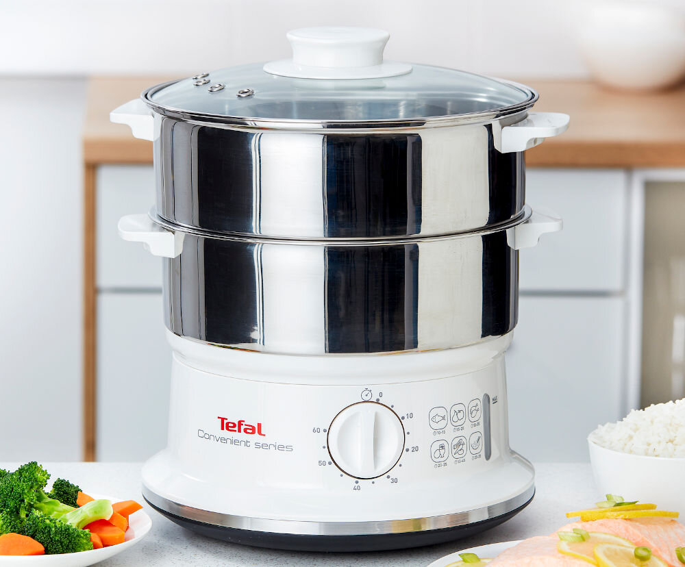 Na obrazie widoczny jest parowar z dwoma metalowymi pojemnikami i szklaną pokrywką. Na urządzeniu znajduje się logo \'Tefal Convenient series\' oraz pokrętło z oznaczeniami czasowymi.