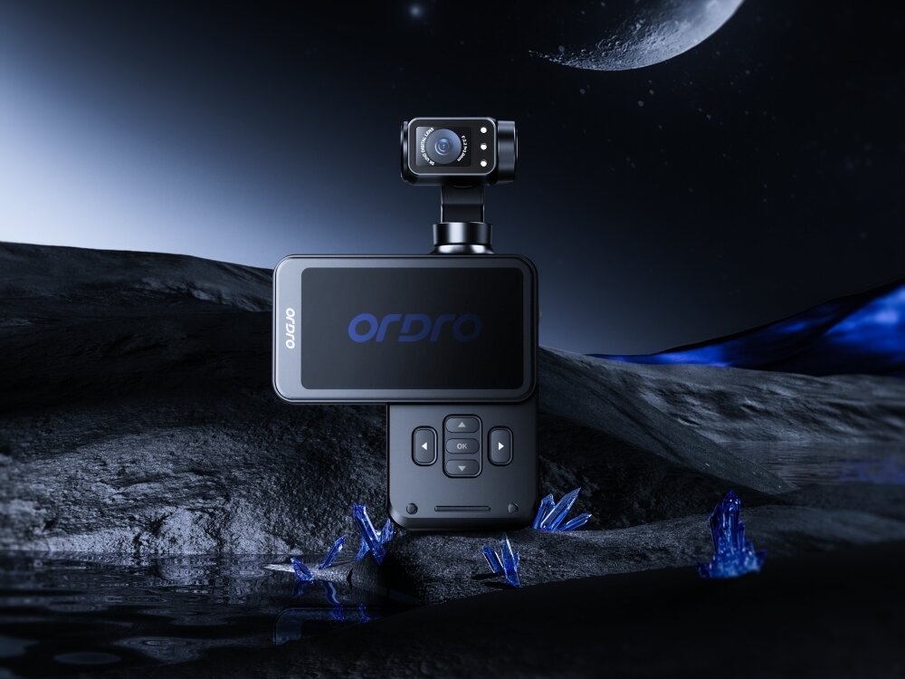Kamera sportowa ORDRO M5 Pocket z wyświetlaczem i przyciskami sterującymi, umieszczona na tle krajobrazu z księżycem i niebieskimi kryształami. Na ekranie widoczne jest logo \'ORDRO\'.