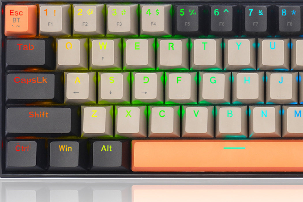 Klawiatura mechaniczna z podświetleniem RGB, posiada klawisze w kolorze beżowym i czarnym z pomarańczowymi akcentami. Widoczne są klawisze takie jak \'Esc\', \'Tab\', \'CapsLk\', \'Shift\', \'Ctrl\', \'Win\', \'Alt\' oraz litery i cyfry z przypisanymi funkcjami F1-F8.