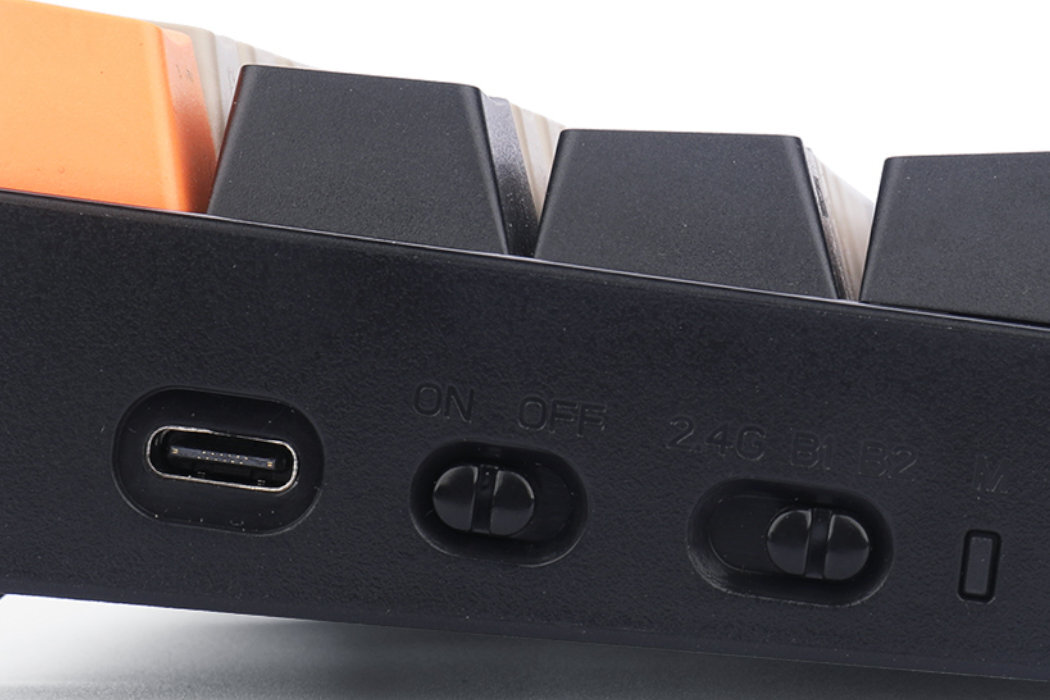 Zbliżenie na bok klawiatury z widocznym portem USB-C oraz dwoma przełącznikami oznaczonymi jako \'ON OFF\' i \'2.4G BT\'.