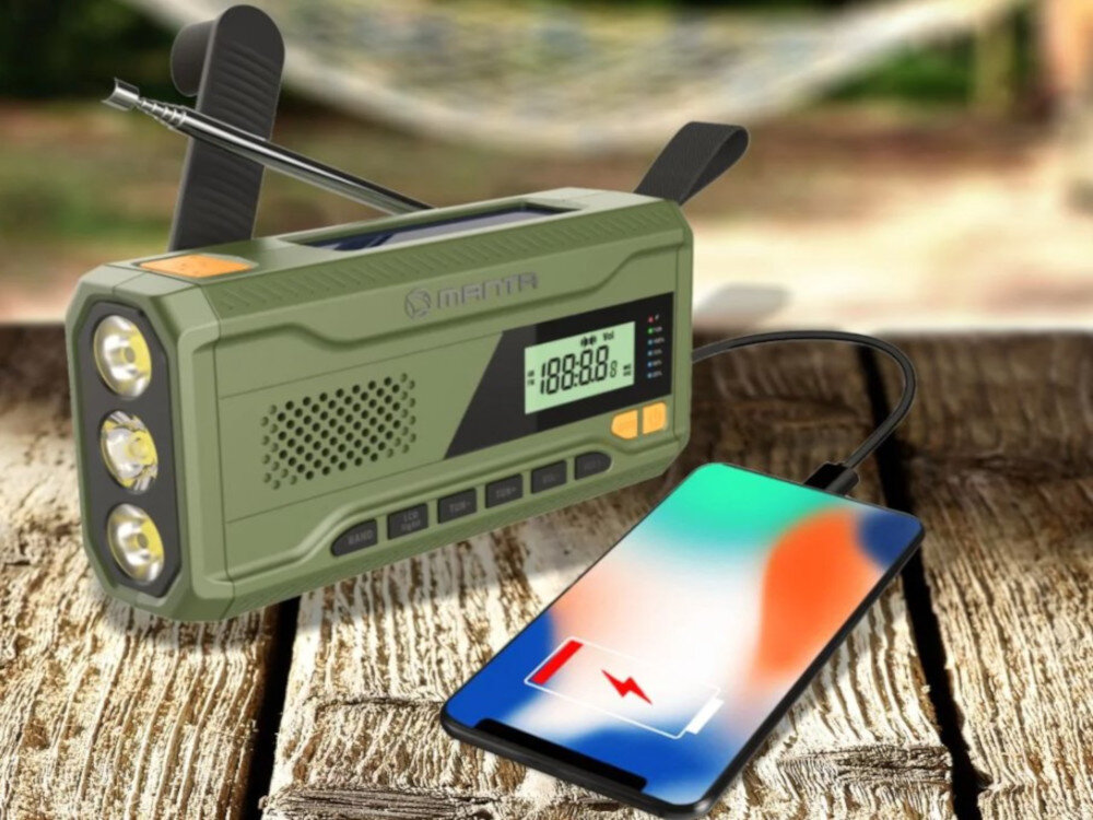 Zielone przenośne radio z wyświetlaczem cyfrowym i trzema latarkami LED, podłączone do smartfona za pomocą kabla. Na obudowie widoczne jest logo \'MANTA\'.