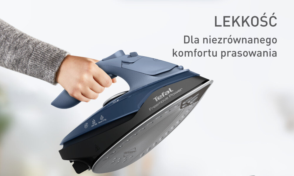 Osoba trzyma żelazko z napisem \'Tefal Freemove Power\'. Obok widoczny jest tekst: \'LEKKOŚĆ Dla niezrównanego komfortu prasowania\'.