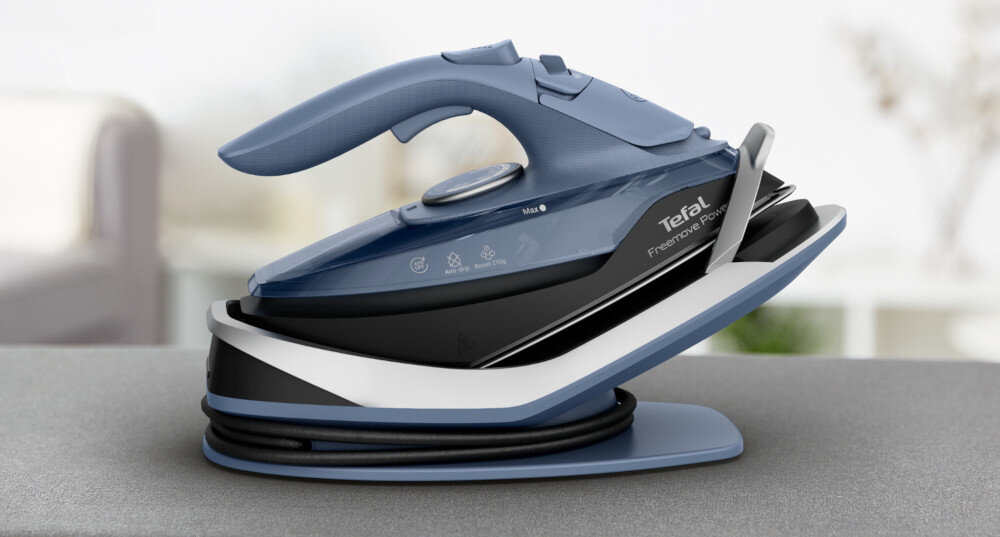 Na obrazie widoczne jest żelazko w kolorze niebieskim i czarnym, umieszczone na podstawce. Na obudowie znajduje się logo \'Tefal Freemove Power\'.