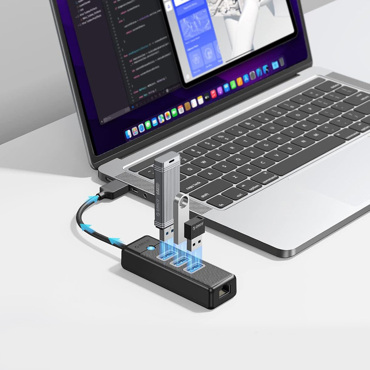 Na obrazie widoczny jest laptop z otwartym ekranem, do którego podłączony jest czarny hub USB z kilkoma portami. Do huba podłączone są różne urządzenia USB, a na jego powierzchni widnieje logo \'Orico\'.