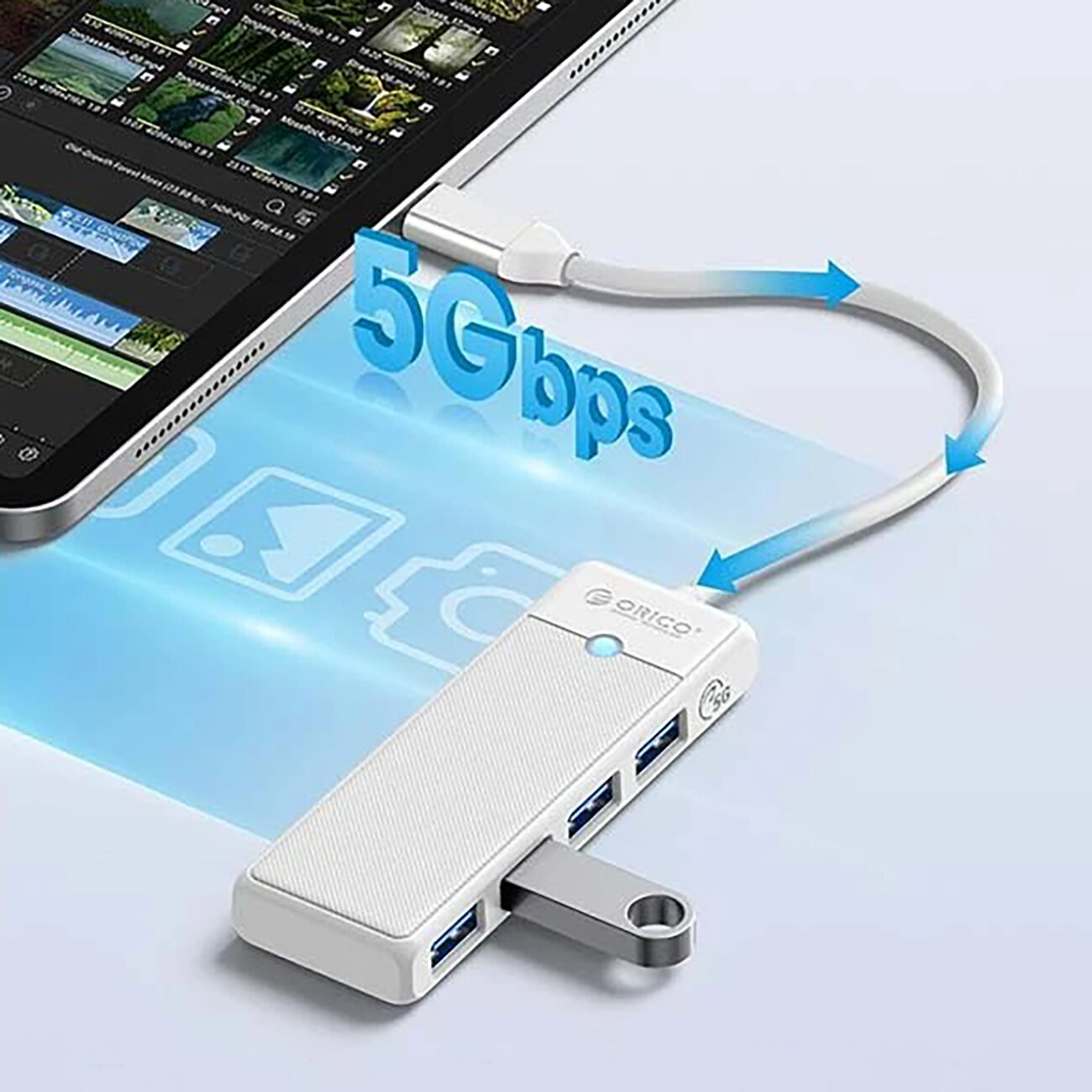 Na obrazie widoczny jest biały hub USB z czterema portami USB-A 3.0, podłączony do tabletu. Obok huba znajduje się napis \'5Gbps\' oraz logo \'Orico\'.