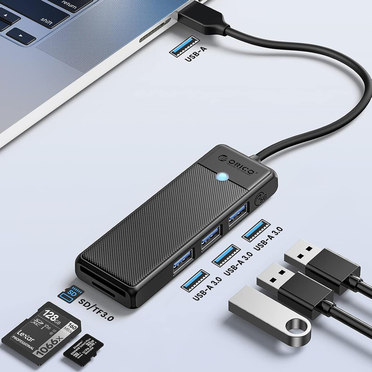Na obrazie widoczny jest czarny hub USB marki Orico z trzema portami USB 3.0 i czytnikiem kart SD/TF. Obok znajdują się karty pamięci, pendrive oraz kable USB, a na hubie widnieje logo \'Orico\'.