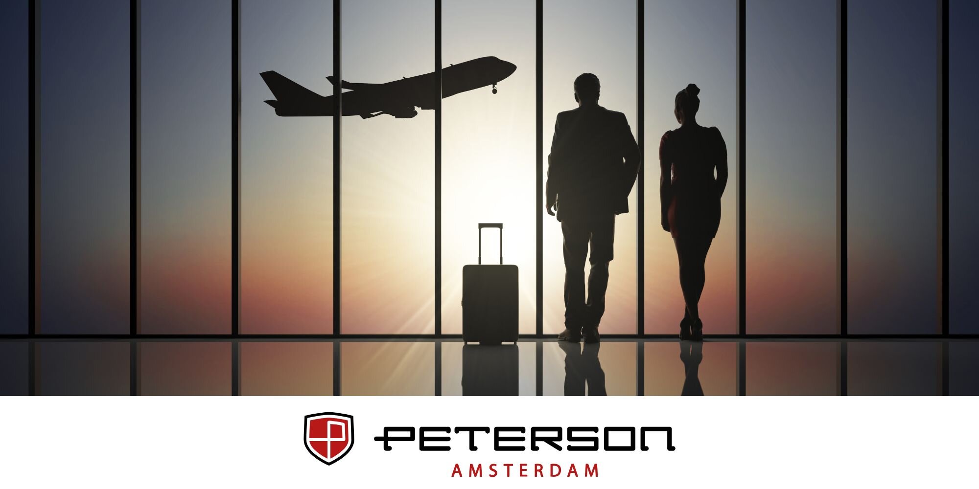 Dwie sylwetki osób z walizką na tle dużych okien, przez które widać odlatujący samolot. Na dole widoczne jest logo \'PETERSON AMSTERDAM\'.