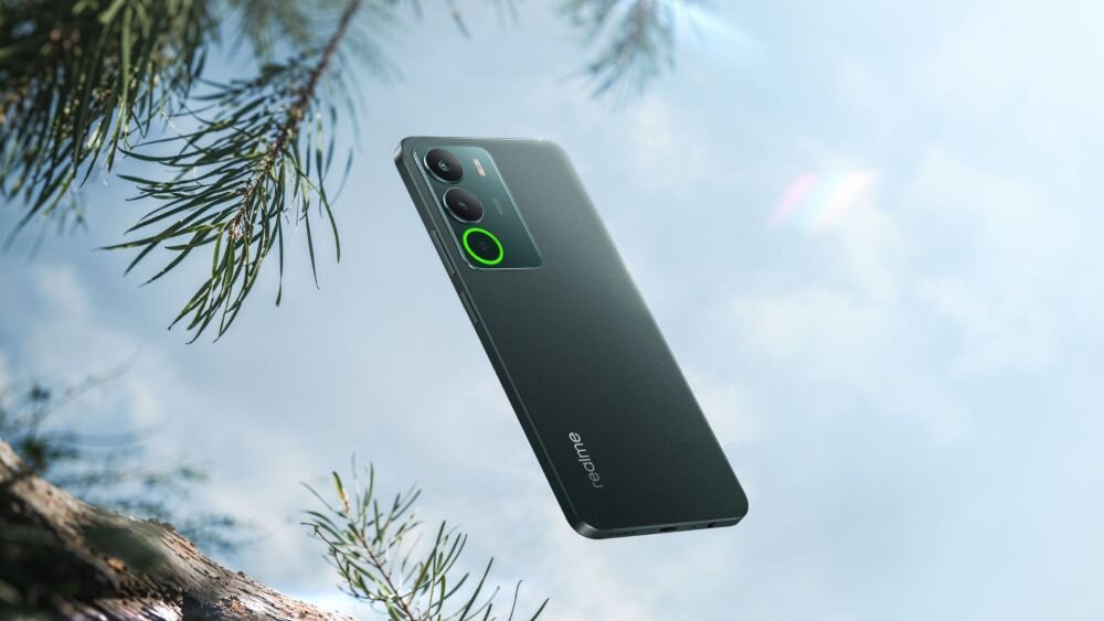 Smartfon w kolorze ciemnym z dwoma aparatami z tyłu, unoszący się na tle nieba i gałęzi drzew. Na obudowie widoczne jest logo \'realme\'.