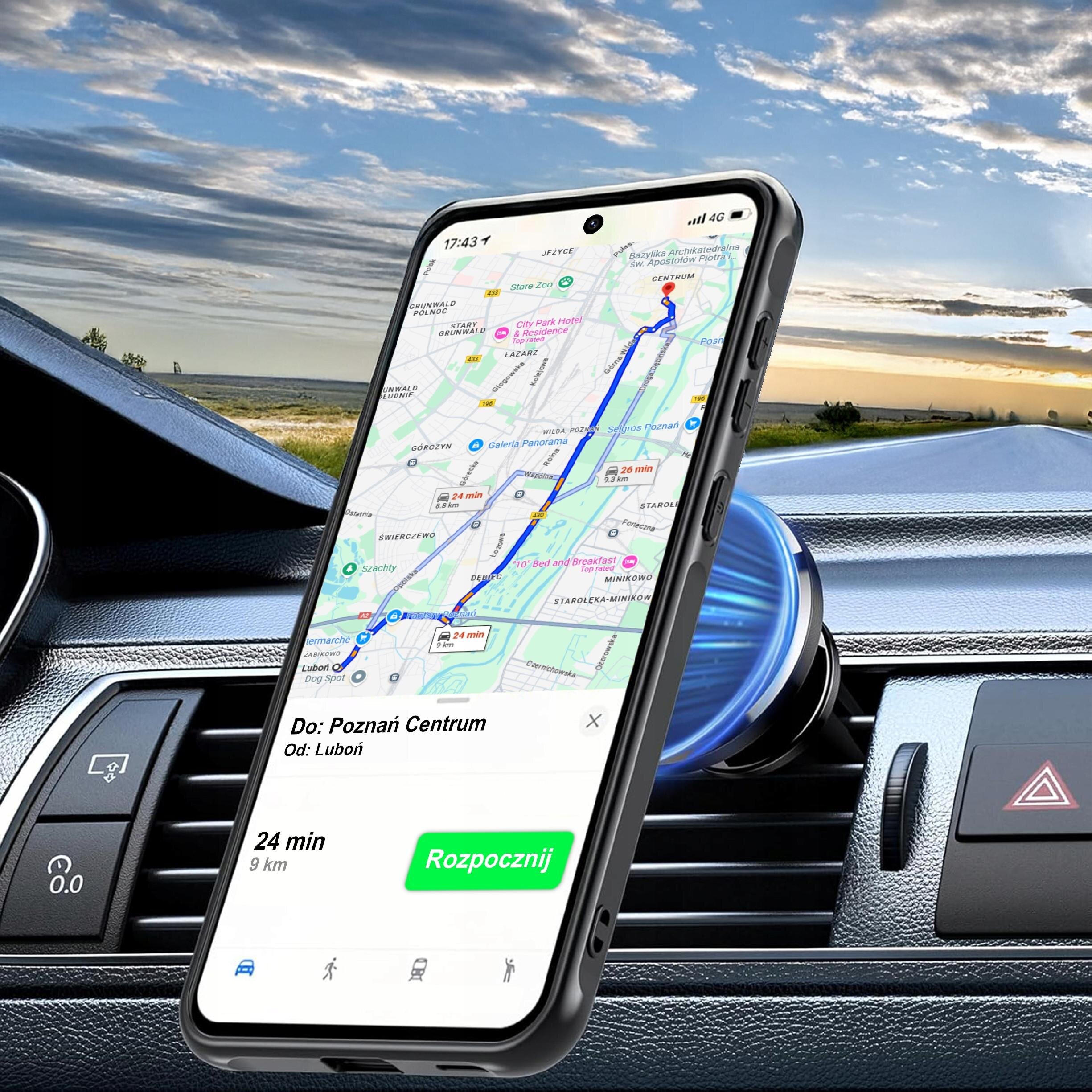 Smartfon w czarnym etui magnetycznym jest zamocowany na uchwycie w samochodzie, wyświetlając mapę z trasą do Poznań Centrum. Na ekranie widoczny jest tekst: \'Do: Poznań Centrum, Od: Luboń, 24 min, 9 km, Rozpocznij\'.