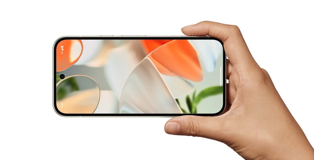 Osoba trzyma smartfon z wyświetlaczem pokazującym abstrakcyjną grafikę w jasnych kolorach. Telefon ma cienkie ramki i centralnie umieszczoną kamerę przednią w górnej części ekranu.