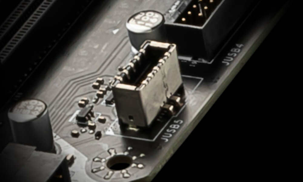 Zbliżenie na fragment płyty głównej z widocznym złączem USB oznaczonym jako \'JUSB3\'. Obok znajdują się kondensatory i inne elementy elektroniczne.