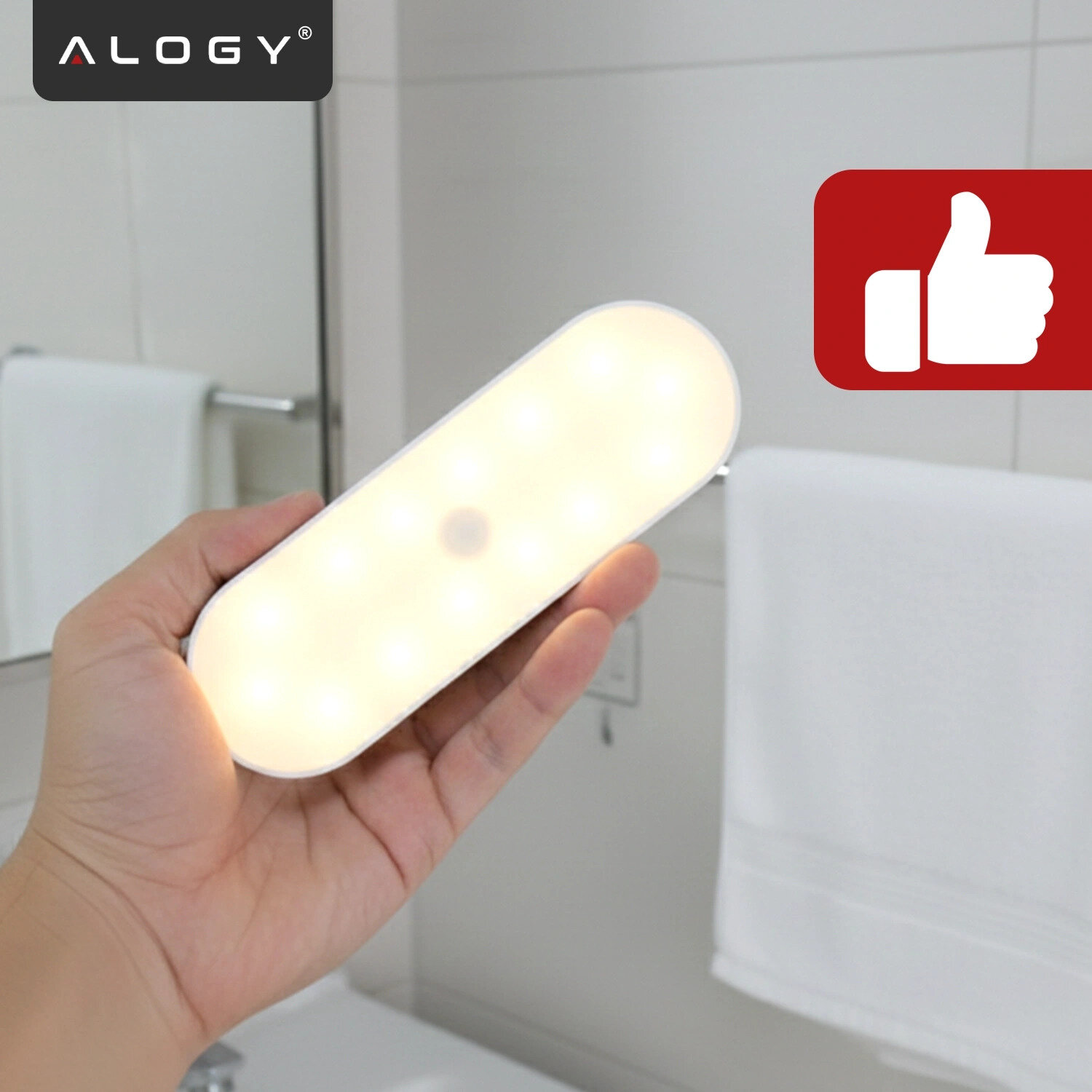 Osoba trzyma w dłoni podłużną, świecącą lampkę LED. W tle widoczne jest logo \'ALOGY\' oraz symbol kciuka w górę na czerwonym tle.