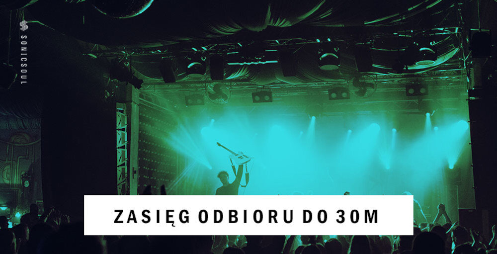 Na scenie widać osobę trzymającą gitarę, otoczoną zielonymi światłami. Na dole obrazu znajduje się napis: \'ZASIĘG ODBIORU DO 30M\'.