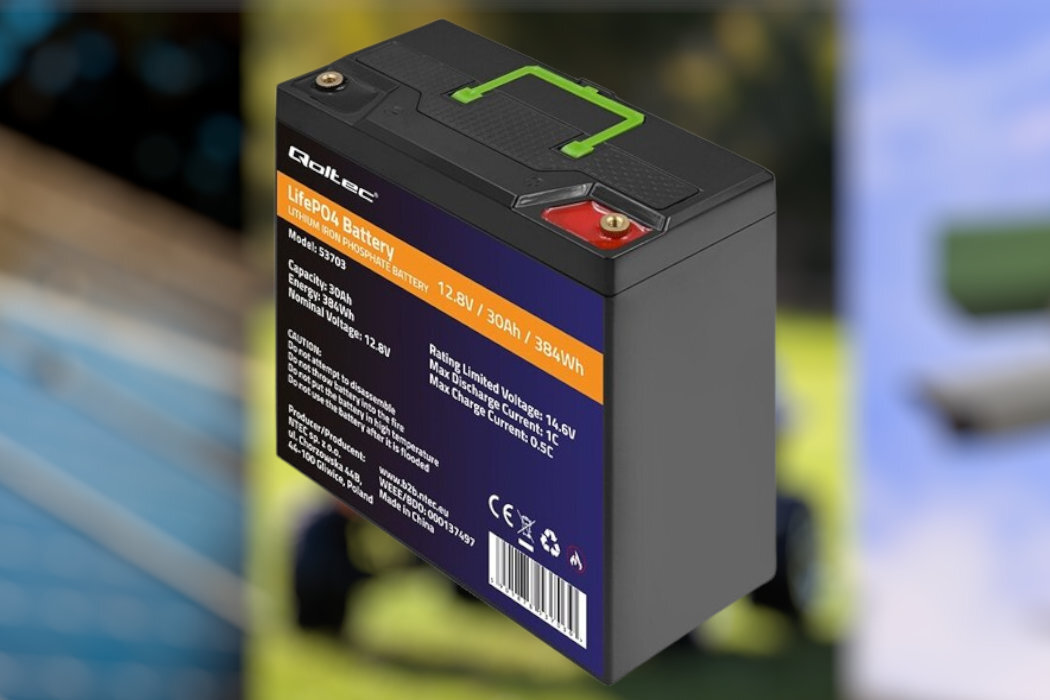 Na obrazie widoczny jest akumulator z napisem \'Qoltec LifePo4 Battery Model: 53703 12.8V / 30Ah / 384Wh\'. Obudowa jest czarna z zielonym uchwytem i posiada oznaczenia techniczne oraz logo producenta.