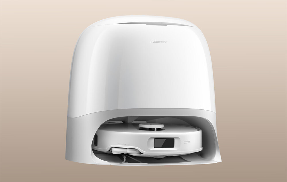 Biały robot sprzątający w stacji dokującej na beżowym tle. Na obudowie widoczne jest logo \'roborock\'.