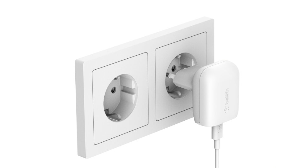 Biała ładowarka sieciowa podłączona do gniazdka elektrycznego. Na ładowarce widoczne jest logo \'belkin\'.