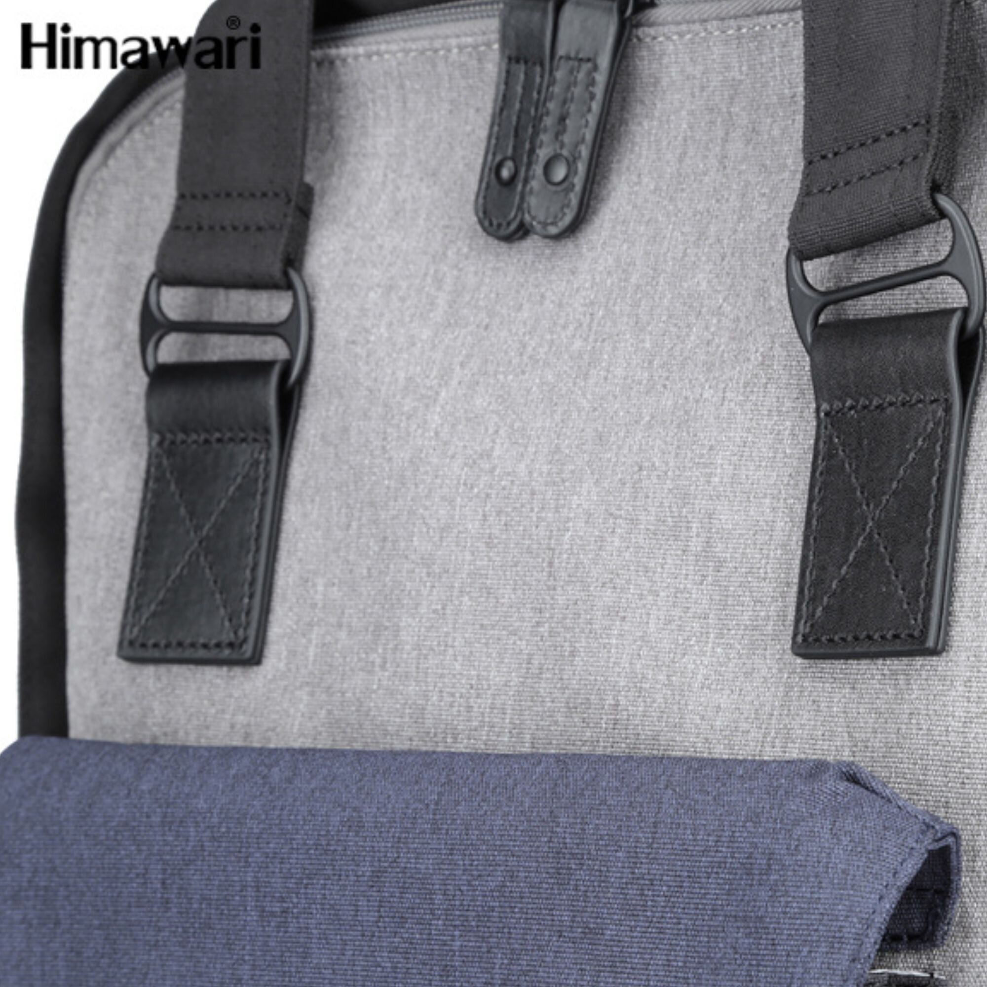 Fragment plecaka z szarym materiałem i czarnymi paskami z klamrami. Widoczne logo \'Himawari\' w lewym górnym rogu.