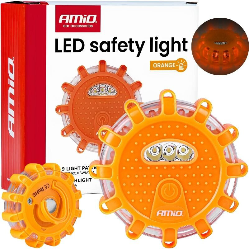 Na obrazie widoczna jest pomarańczowa lampa ostrzegawcza z napisem \'Amio\' oraz opakowanie z tekstem \'LED safety light\' i \'ORANGE\'. Lampa ma okrągły kształt z wypustkami i widocznymi diodami LED.