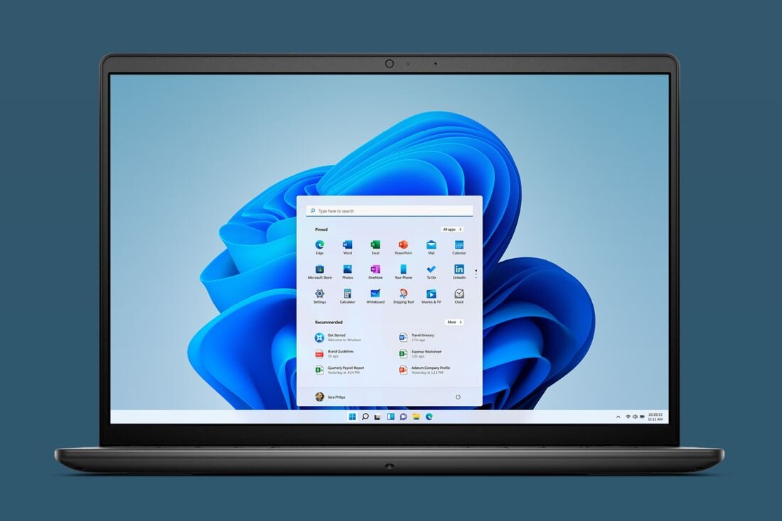 Laptop z wyświetlaczem pokazującym ekran startowy systemu Windows 11 z ikonami aplikacji. Obudowa jest ciemna, a ekran otoczony cienką ramką.