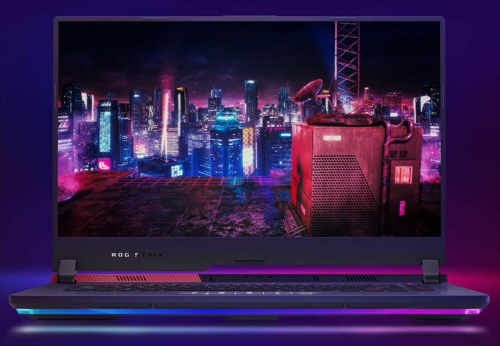 Laptop z wyświetlaczem pokazującym futurystyczne miasto nocą, z neonowymi światłami i budynkami. Na obudowie widoczne jest logo \'ROG STRIX\'.
