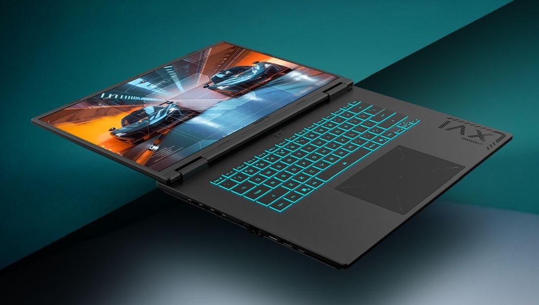 Laptop z podświetlaną klawiaturą i wyświetlaczem pokazującym wyścigowe samochody. Obudowa ma nowoczesny design z widocznym logo producenta.