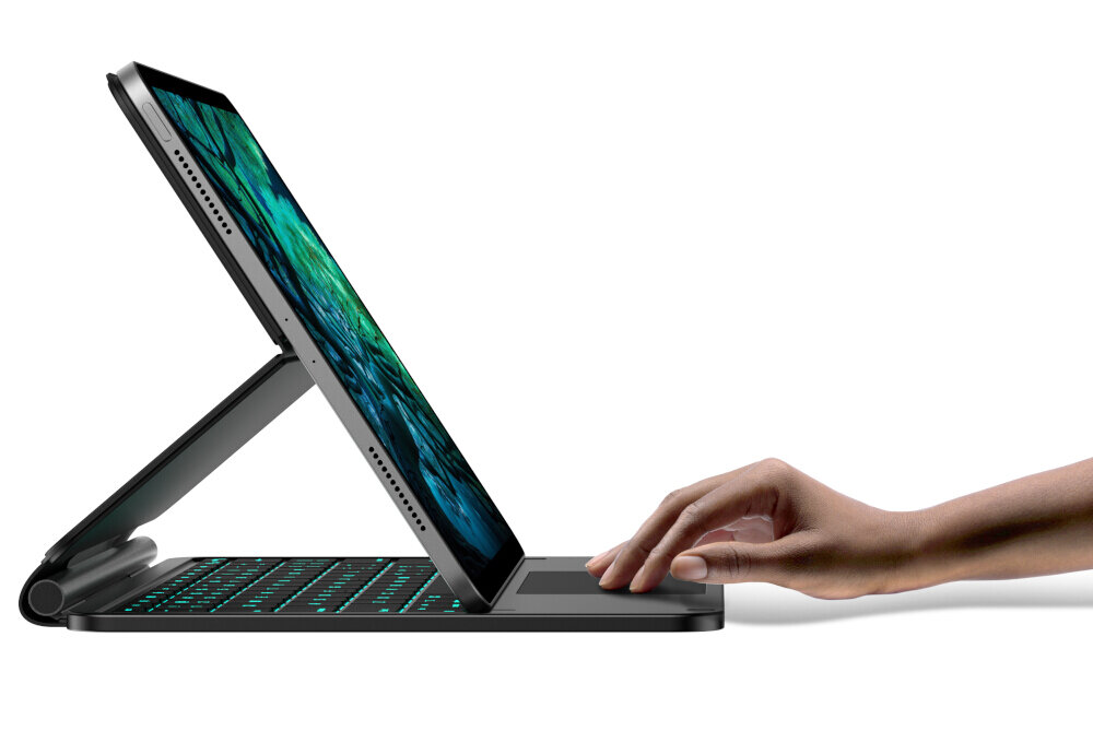 Obraz przedstawia tablet umieszczony na czarnej klawiaturze z podświetleniem, z ręką dotykającą powierzchni klawiatury. Ekran tabletu wyświetla kolorowy wzór.