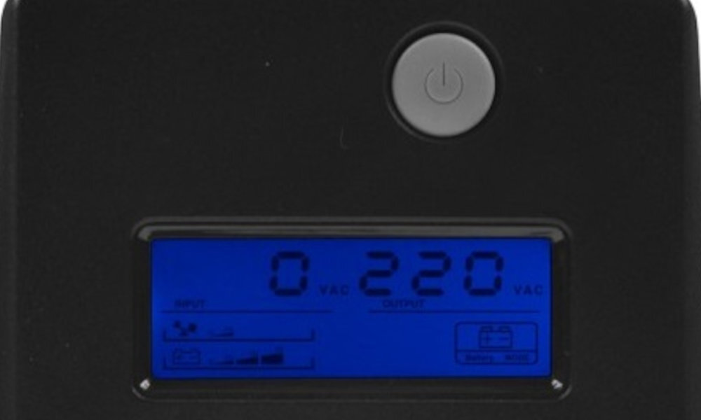 Czarny panel zasilacza UPS z niebieskim wyświetlaczem LCD pokazującym wartości \'0 VAC\' i \'220 VAC\'. Nad wyświetlaczem znajduje się okrągły przycisk z symbolem zasilania.