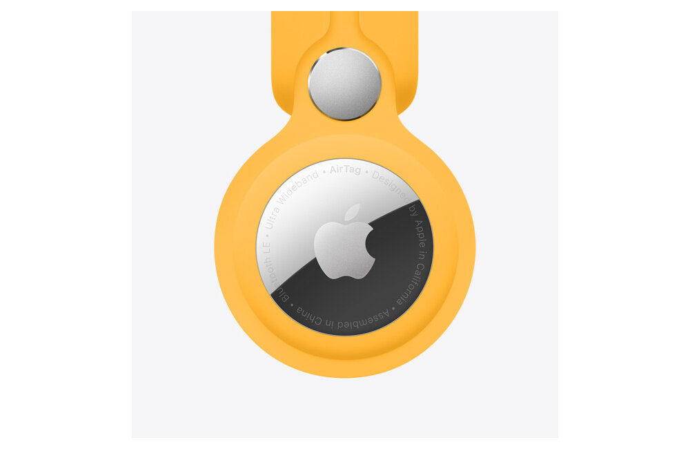Na obrazie widoczny jest lokalizator w żółtym etui z logo Apple na środku. Wokół logo znajduje się tekst: \'Ultra Wideband • AirTag • Designed by Apple in California • Assembled in China\'.