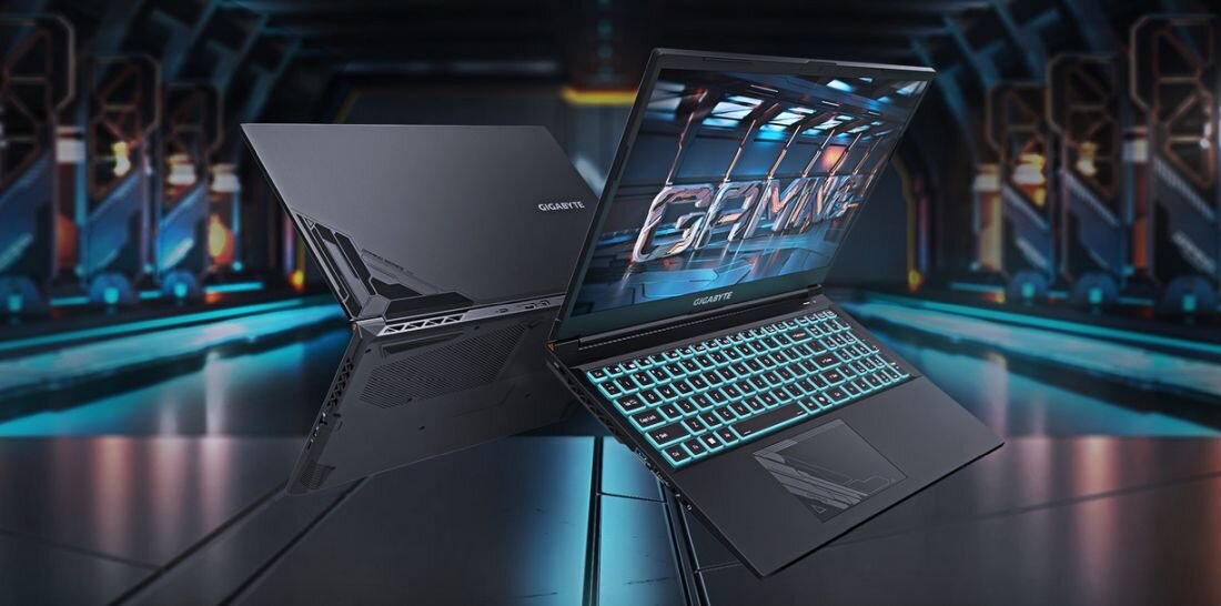 Dwa laptopy GIGABYTE z podświetlaną klawiaturą, jeden otwarty z widocznym ekranem, drugi zamknięty z widocznym logo GIGABYTE. Tło przedstawia futurystyczne wnętrze z metalicznymi elementami.