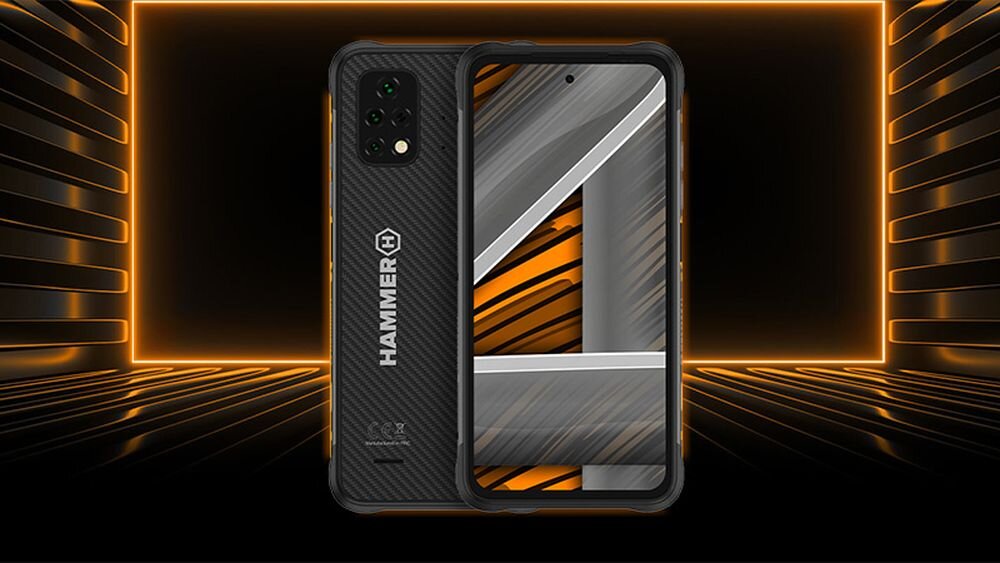 Na obrazie widoczny jest smartfon z napisem \'HAMMER\' na tylnej obudowie. Ekran urządzenia wyświetla abstrakcyjny wzór z pomarańczowymi i szarymi liniami.