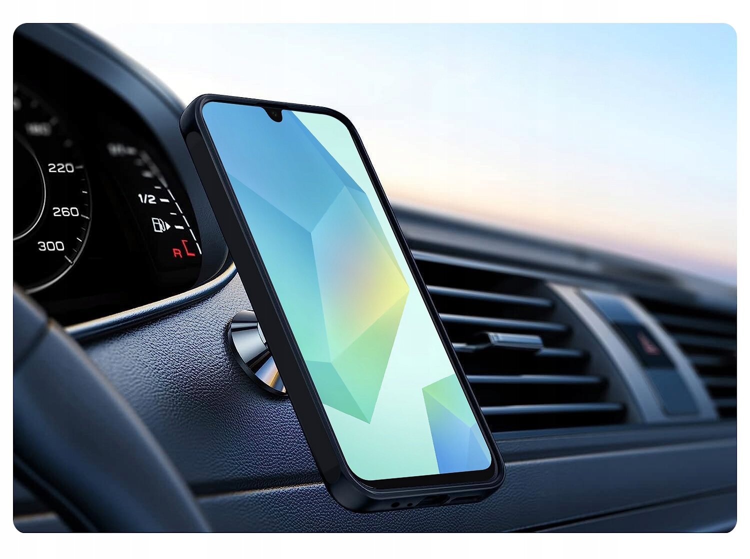 Smartfon w etui jest zamocowany na uchwycie magnetycznym w samochodzie, na tle deski rozdzielczej z widocznym prędkościomierzem. Ekran telefonu wyświetla abstrakcyjny wzór w pastelowych kolorach.