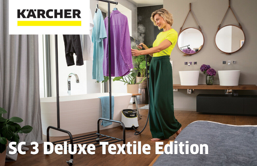 Osoba używa parownicy do prasowania ubrań zawieszonych na stojaku. W tle widoczne są elementy łazienki, a na obrazie znajduje się logo \'KÄRCHER\' oraz napis \'SC 3 Deluxe Textile Edition\'.