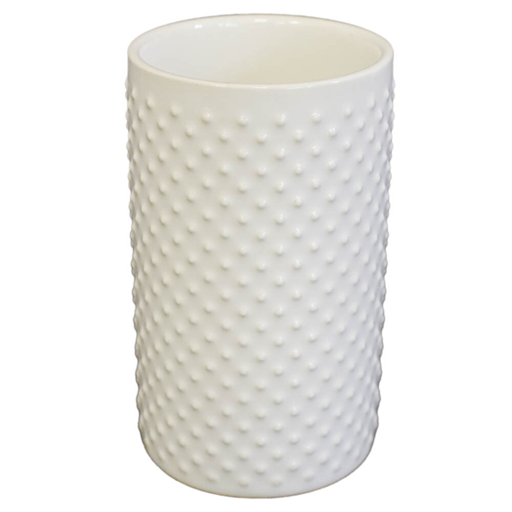 Biały, ceramiczny kubek o cylindrycznym kształcie z wypukłym wzorem w kropki na powierzchni.