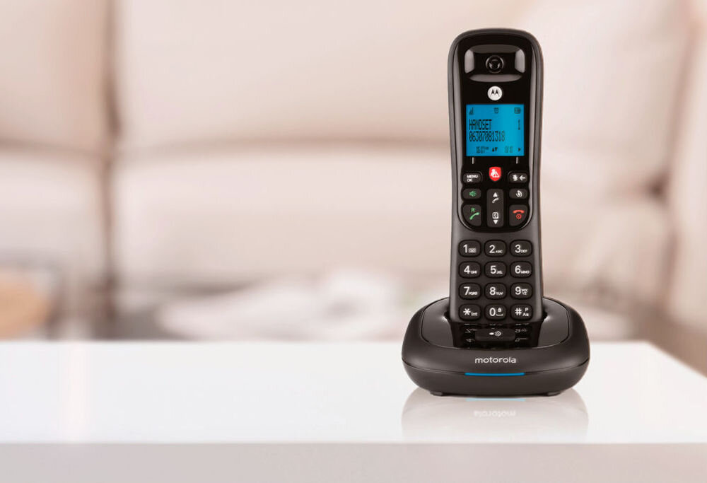 Czarny telefon bezprzewodowy z wyświetlaczem i klawiaturą numeryczną znajduje się na stacji dokującej. Na ekranie widoczny jest tekst: \'HARVECT 0800783103\'.