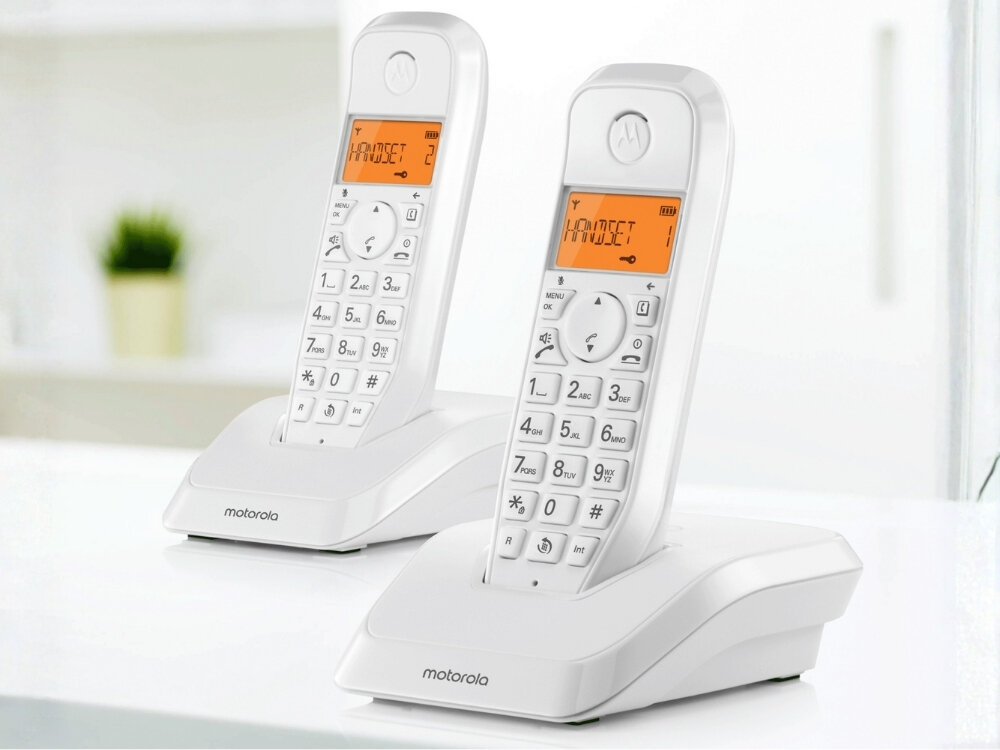 Na obrazie znajdują się dwa białe telefony bezprzewodowe z wyświetlaczami pokazującymi tekst \'HANDSET 2\'. Na podstawach telefonów widoczne jest logo \'motorola\'.