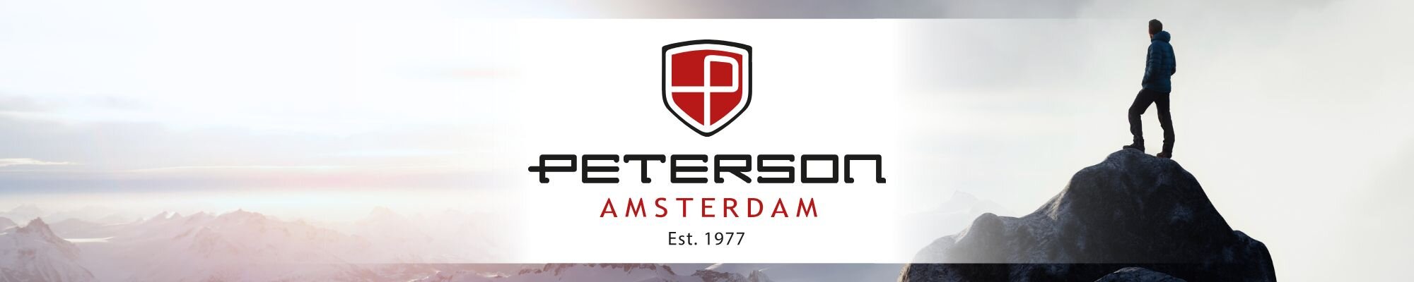 Logo Peterson z napisem \'AMSTERDAM Est. 1977\' na tle krajobrazu górskiego z osobą stojącą na szczycie.