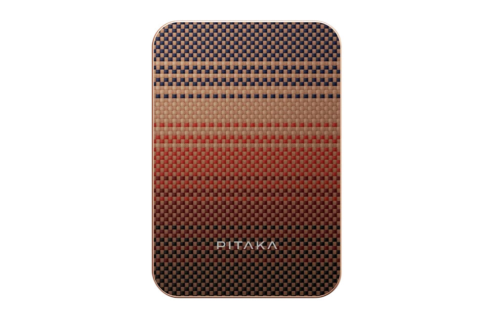Prostokątny powerbank z wzorem w kratkę w odcieniach brązu, czerwieni i czerni. Na dole widoczne jest logo \'PITAKA\'.