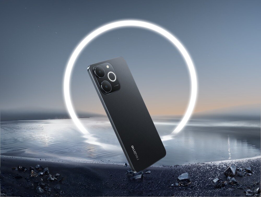 Smartfon w kolorze czarnym z trzema aparatami na tylnej obudowie, na tle krajobrazu z wodą i świetlistym okręgiem. Na obudowie widoczne jest logo \'realme\'.