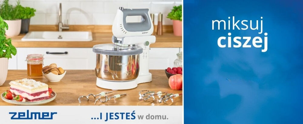 Na blacie kuchennym stoi mikser z metalową misą, obok znajdują się składniki do pieczenia i ciasto. Na obrazie widoczny jest tekst: \'zelmer ...I JESTEŚ w domu.\' oraz \'miksuj ciszej\'.