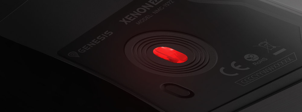Zdjęcie przedstawia spód myszy komputerowej z widocznym czerwonym sensorem optycznym. Na obudowie widnieje tekst: \'GENESIS XENON 220 MODEL: NMG-1527\' oraz symbole certyfikacyjne CE i RoHS.