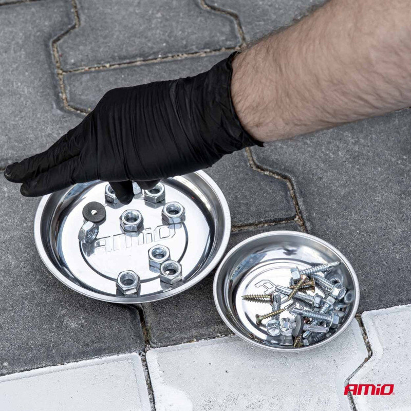 Na obrazie widoczne są dwie metalowe miski magnetyczne z napisem \'AMiO\', wypełnione śrubami i nakrętkami. Obok misek znajduje się ręka w czarnej rękawiczce, a w prawym dolnym rogu widnieje logo \'AMiO\'.