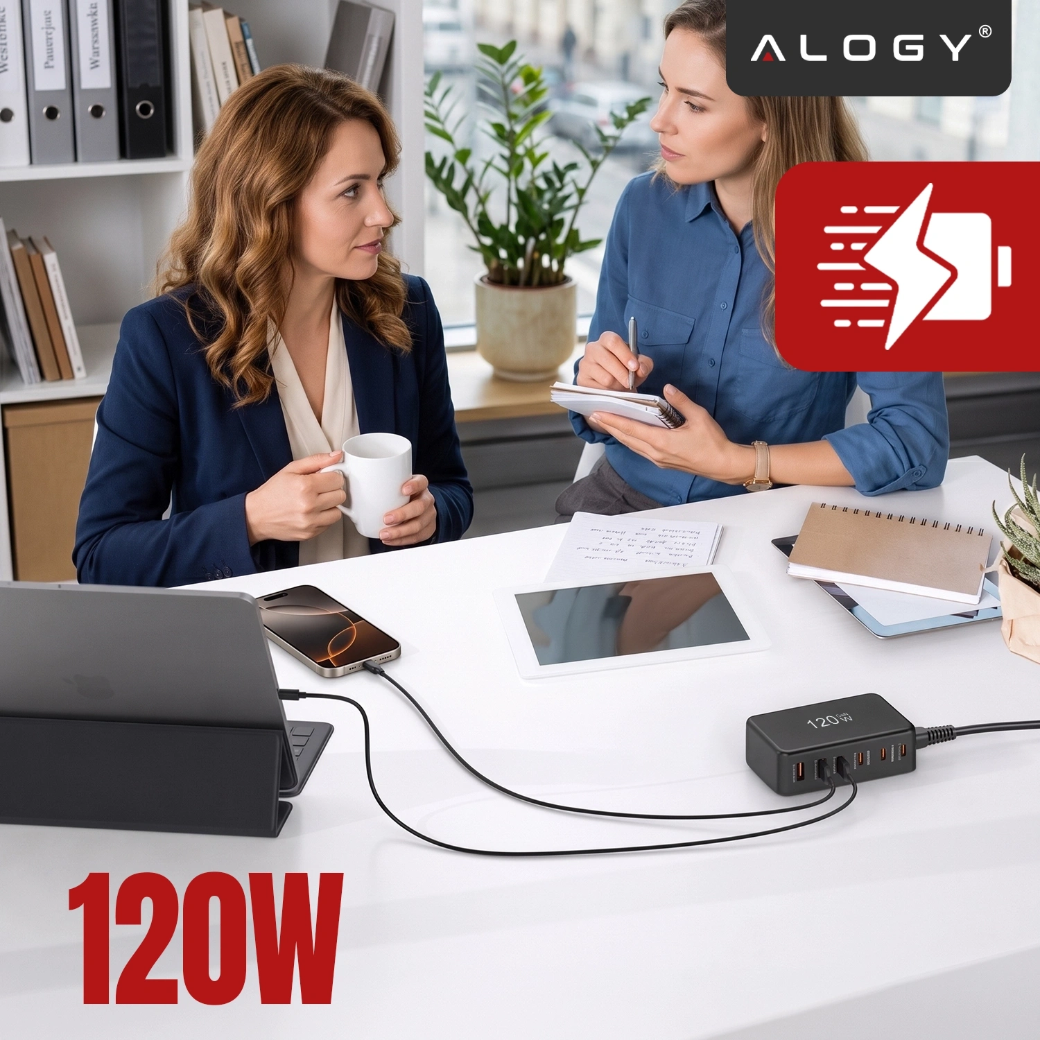 Na biurku znajduje się czarna ładowarka z sześcioma portami, podłączona do laptopa i telefonu. Widoczne jest logo \'ALOGY\' oraz napis \'120W\'.
