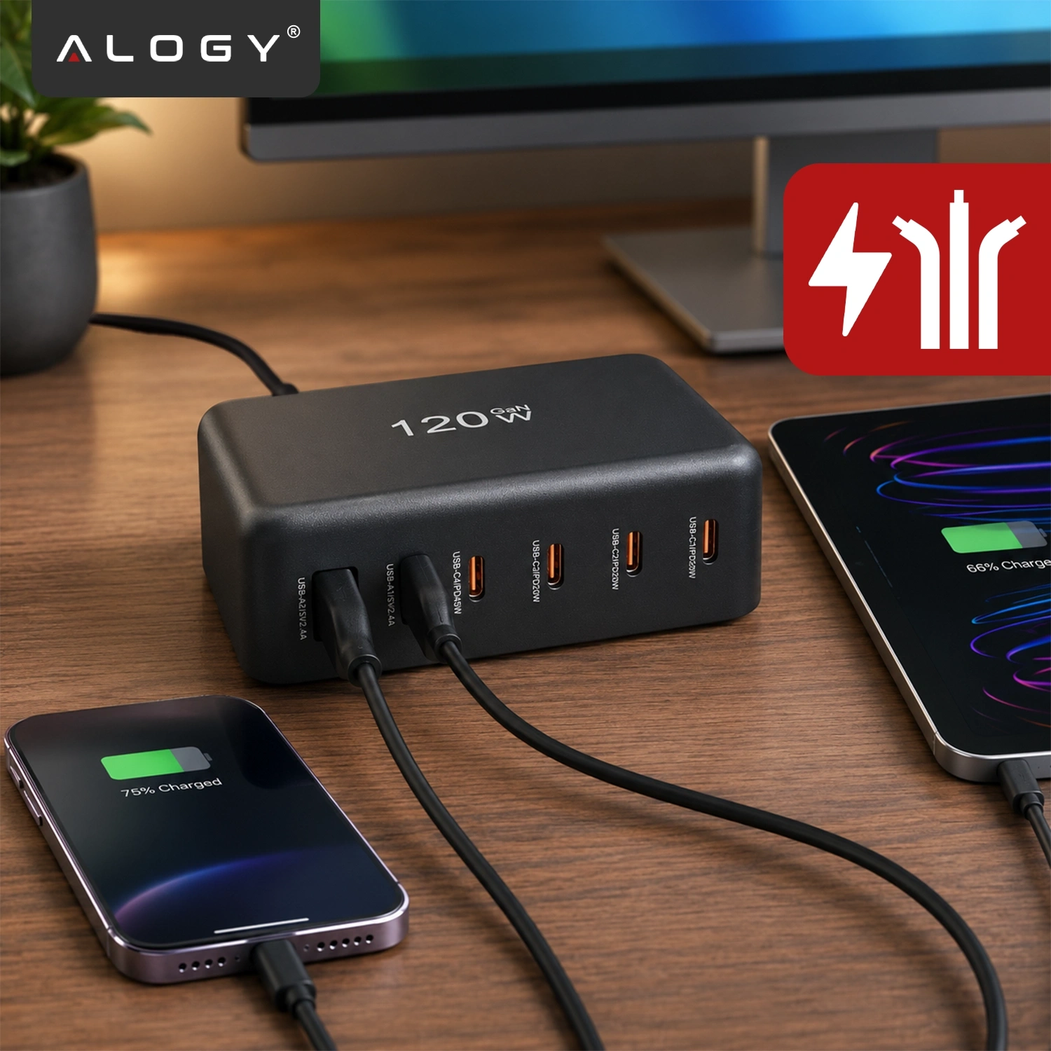 Na drewnianym biurku znajduje się czarna ładowarka z napisem \'120W\', podłączona do telefonu i tabletu. W lewym górnym rogu widoczne jest logo \'ALOGY\'.