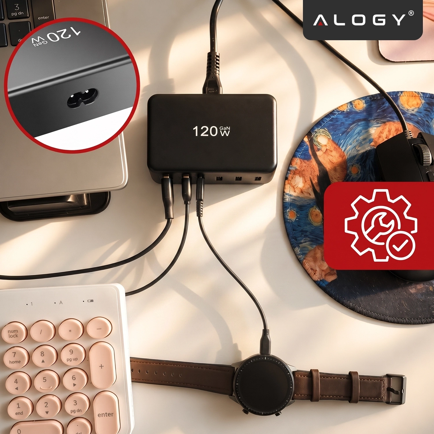 Na biurku znajduje się czarna ładowarka z napisem \'120 GAN W\', do której podłączone są różne urządzenia. W prawym górnym rogu widoczne jest logo \'ALOGY\'.