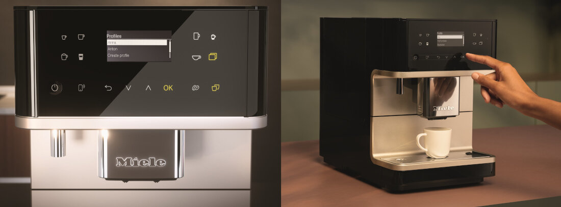 Na zdjęciu widoczny jest ekspres do kawy z wyświetlaczem, na którym widać menu z opcjami: Profiles, Ristretto, Espresso, Coffee, Coffee pot. Logo \'Miele\' znajduje się na przedniej części urządzenia, a obok ekspresu stoi filiżanka z kawą.