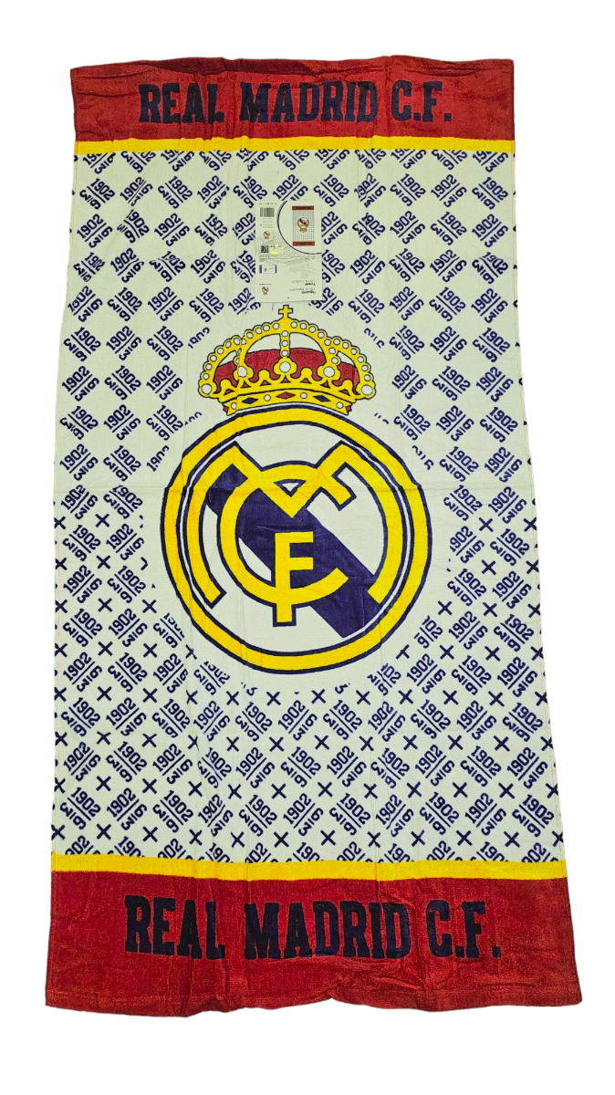 Ręcznik z dużym logo Real Madrid C.F. na tle wzoru z powtarzającymi się napisami \'1902\' i \'Real Madrid\'. Na górze i dole ręcznika znajduje się czerwony pas z czarnym napisem \'REAL MADRID C.F.\'.